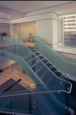 Laminated glass railing along an interior staircase and landing.